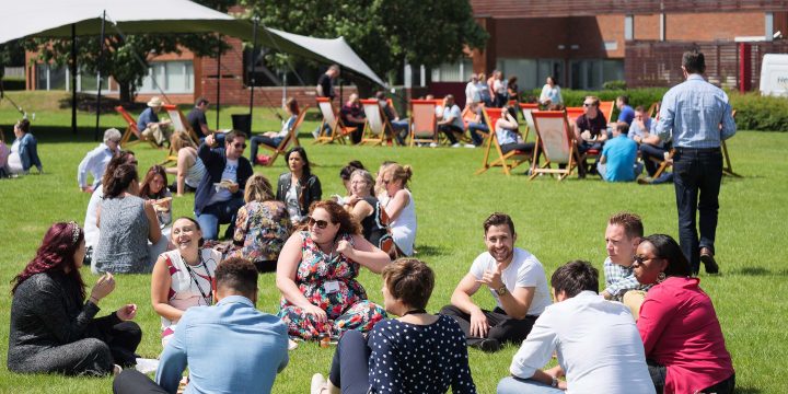 people sitting outside on the grass on a sunny day
