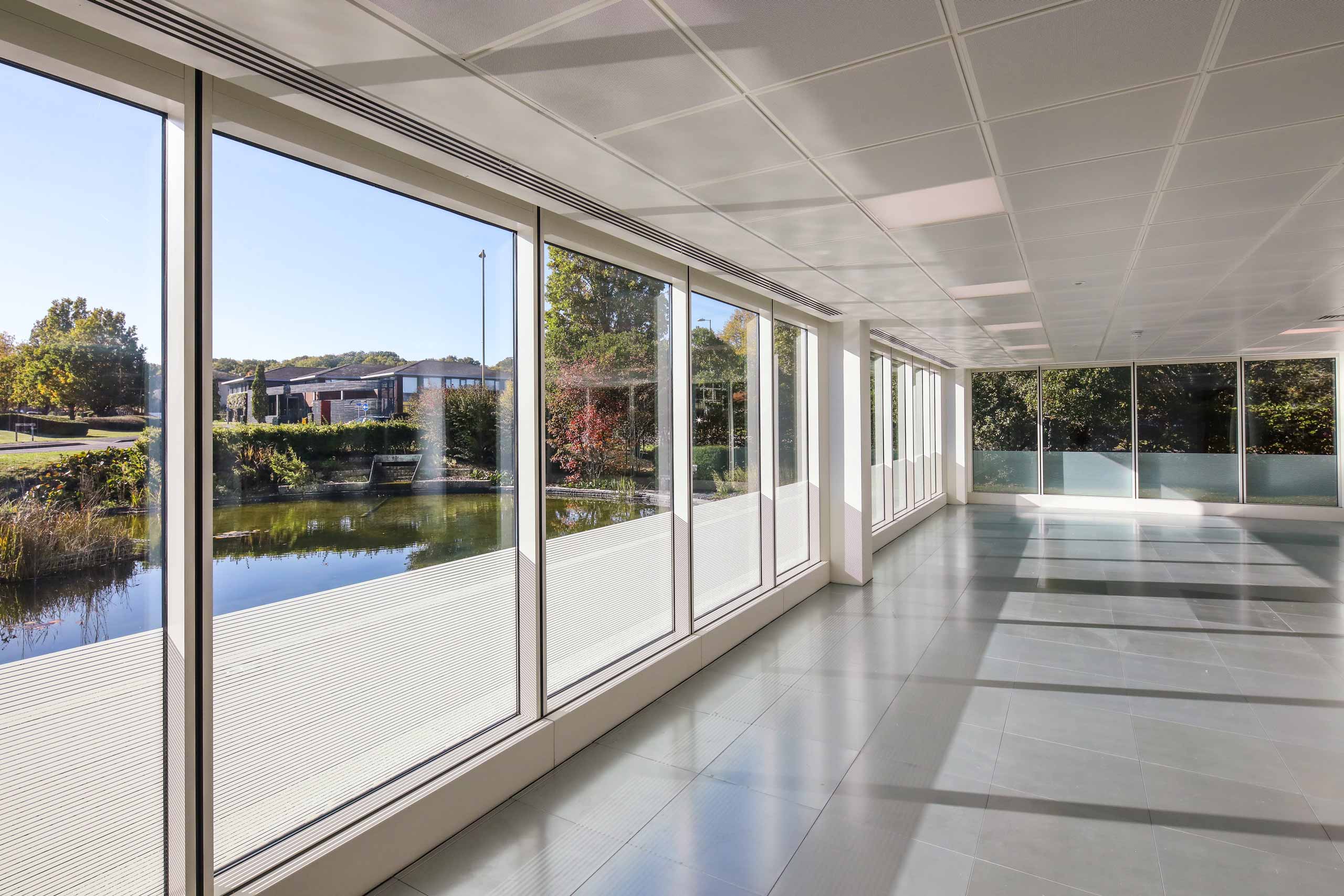 A hallway with large windows and a view of a pond.