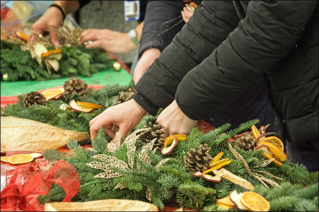 A group of people putting together a christmas wreath.