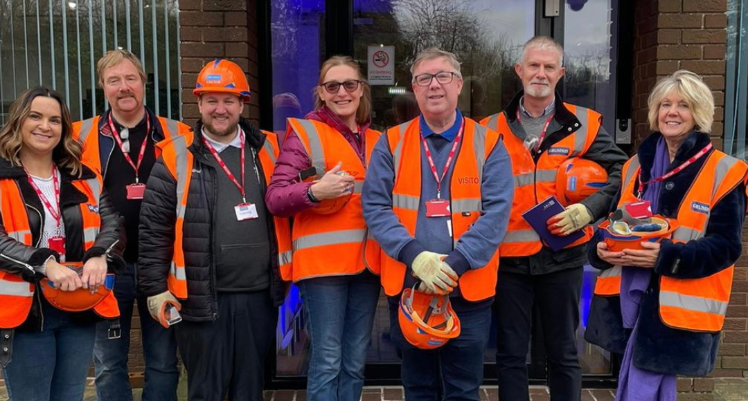 A group of people in orange vests standing in front of a building.