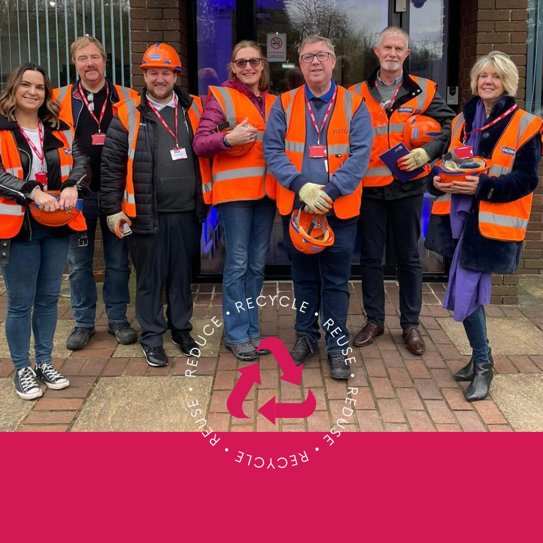 A group of people in orange vests standing in front of a building.