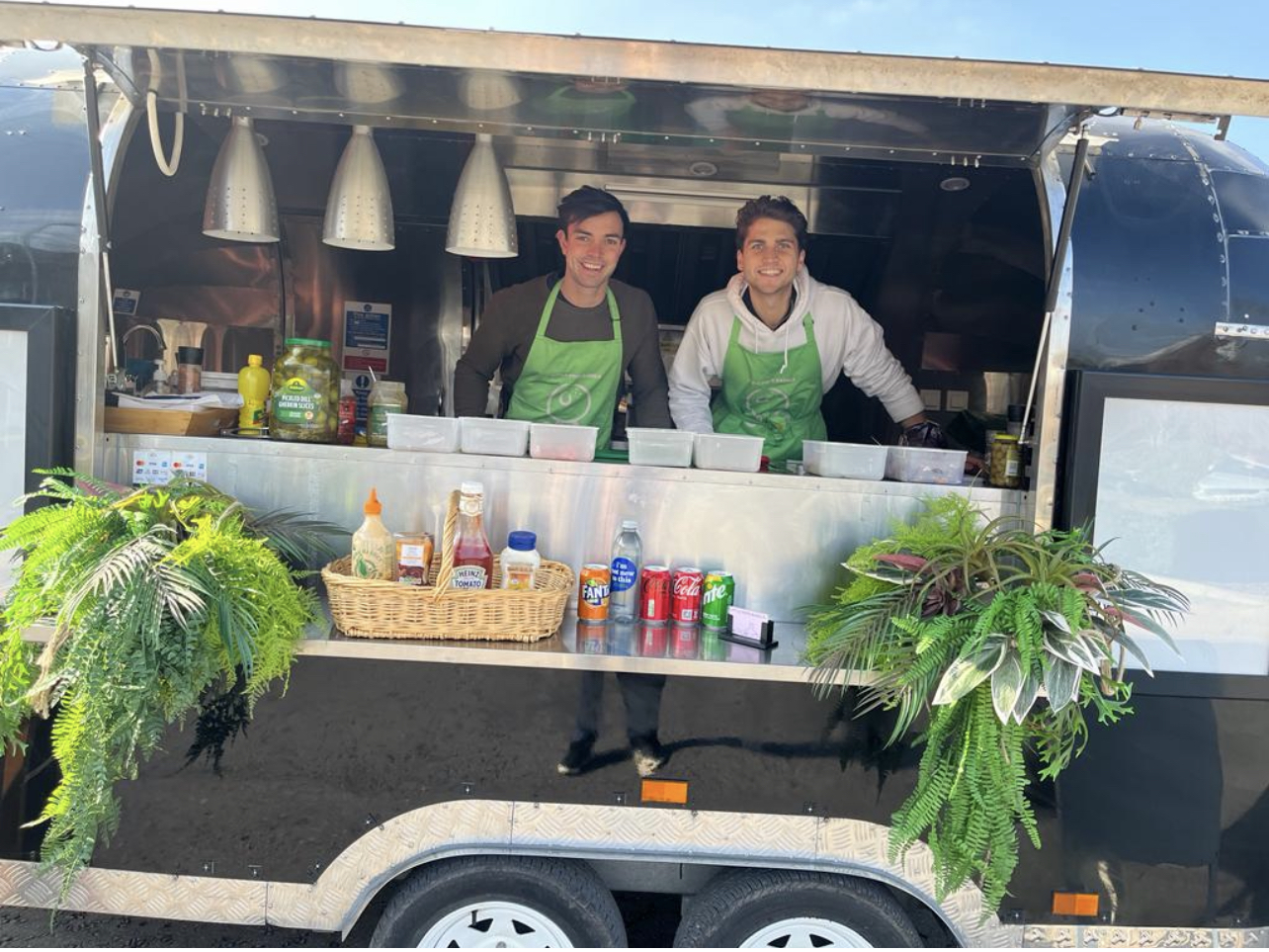 Two men standing in front of a food truck.