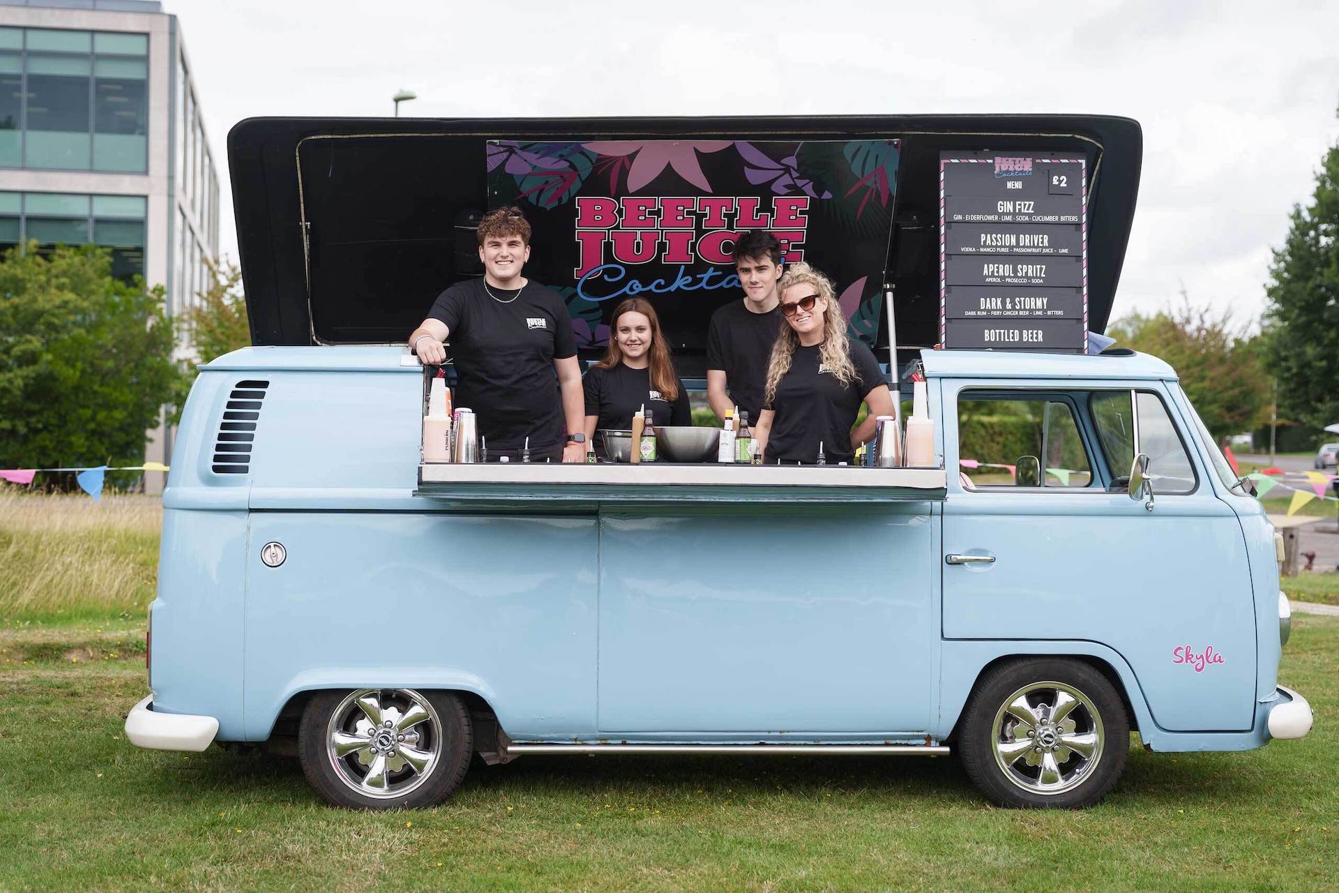 A group of people standing in front of a blue vw bus.